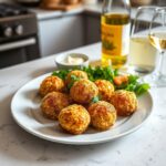 Homemade arancini served with a fresh side salad, garlic aioli, and a glass of white wine on a modern kitchen countertop, showcasing a Mediterranean-inspired presentation.